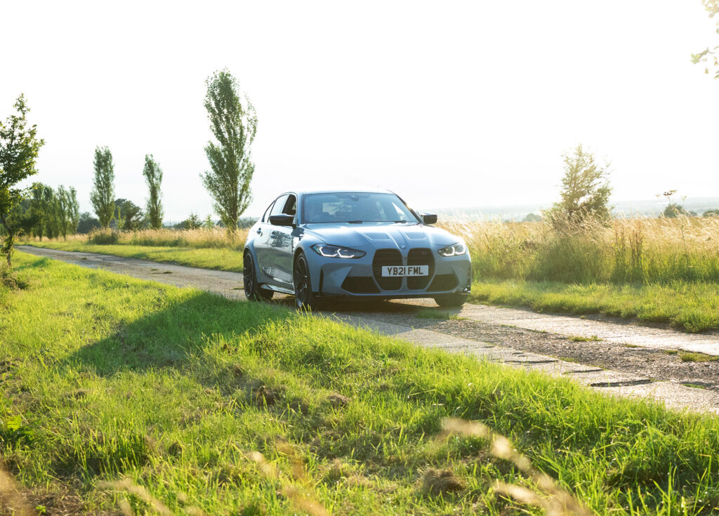 BMW car drives down a road amongst fields