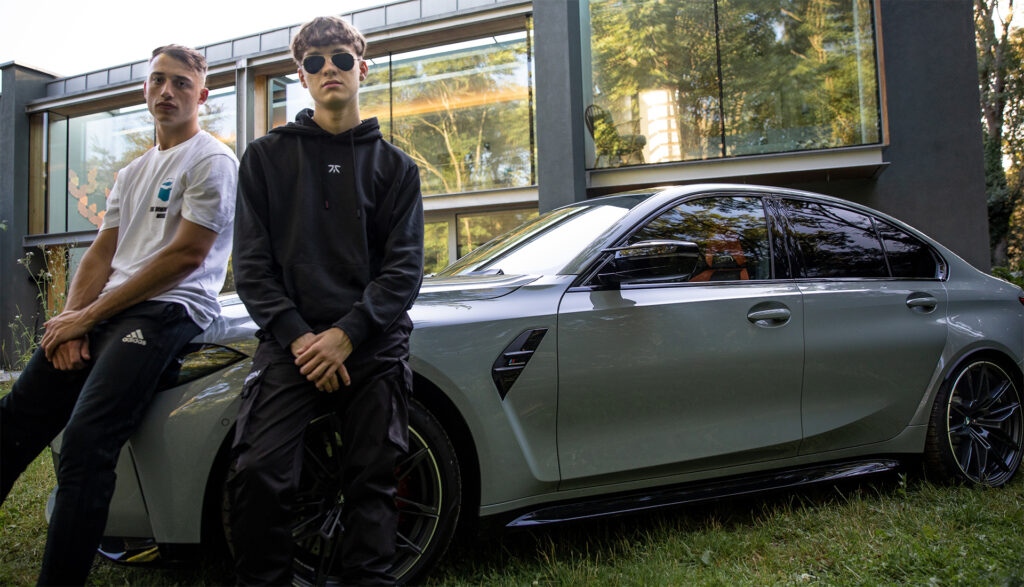 Two e-sports gamer sit on the bonnet of a BMW car