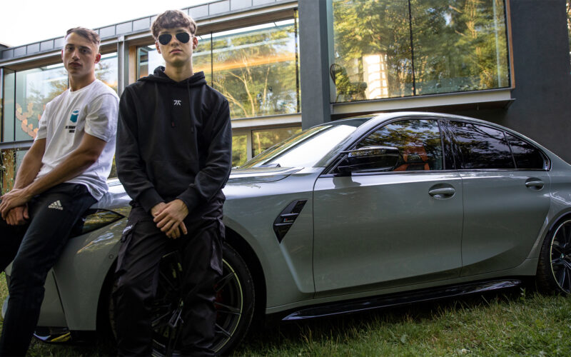 Two e-sports gamer sit on the bonnet of a BMW car