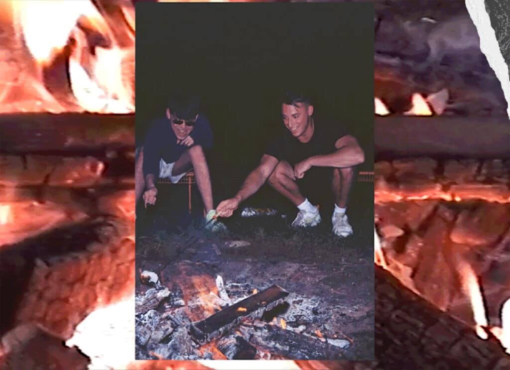 Two young men toast marshmallows over a fire