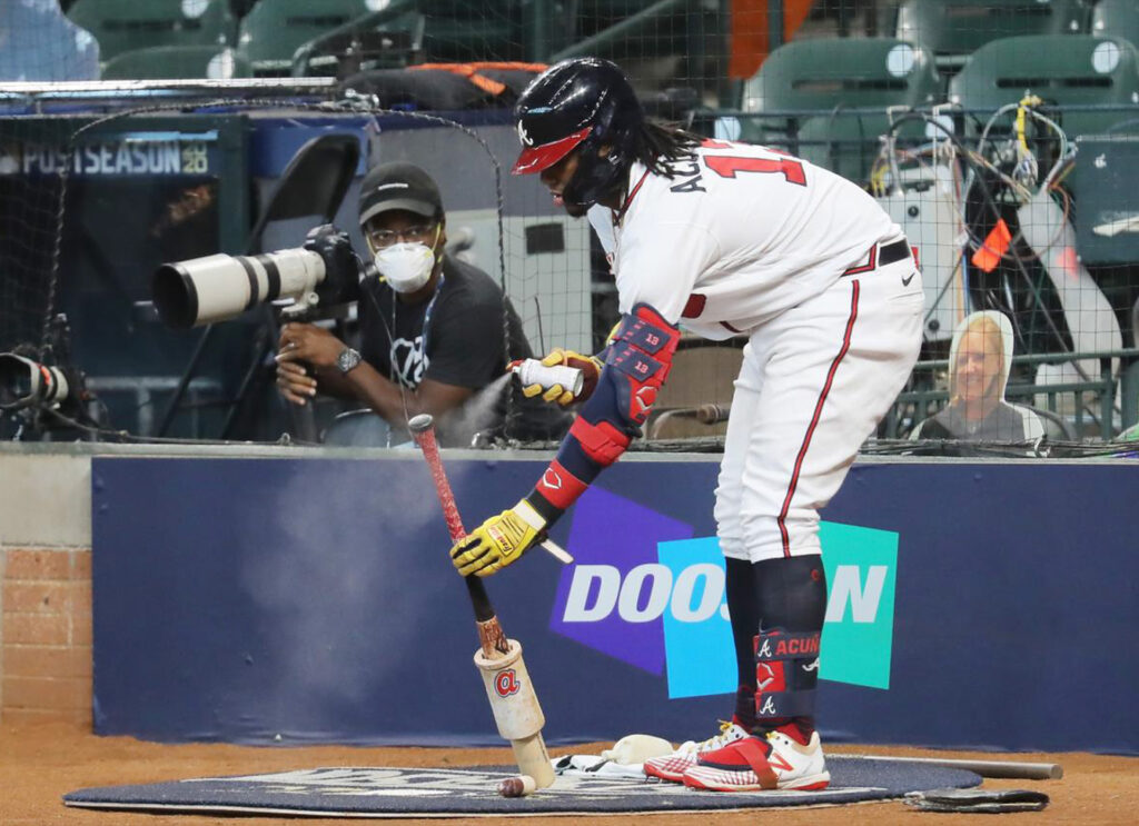 Baseball player sprays the grip of his bat